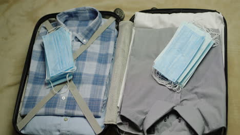 Man-puts-clothes,-protective-masks-and-antiseptic-in-a-suitcase-2