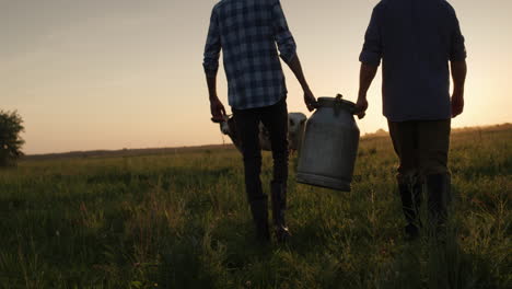 Two-farmers-carry-a-can-through-the-pasture