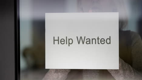 Employee-Hangs-On-The-Door-Ad-Help-Wanted