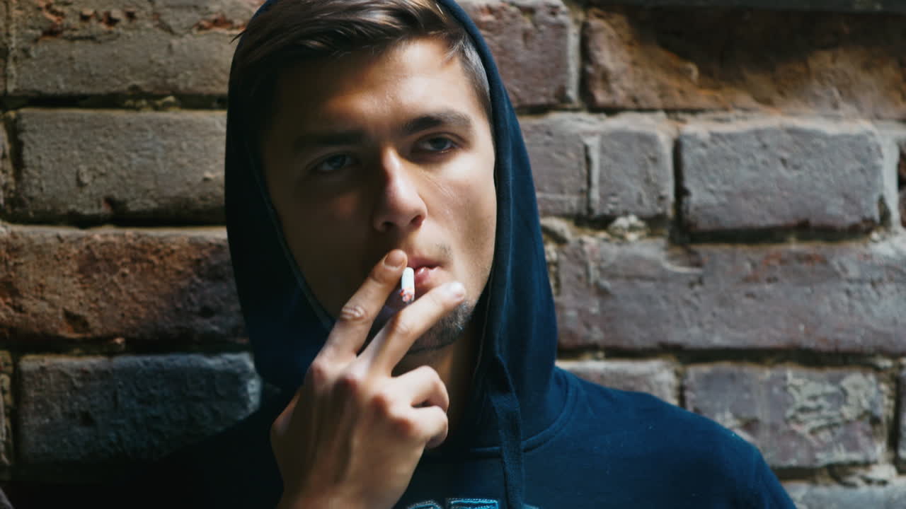 Premium stock video - Sad young man smoking in an abandoned building