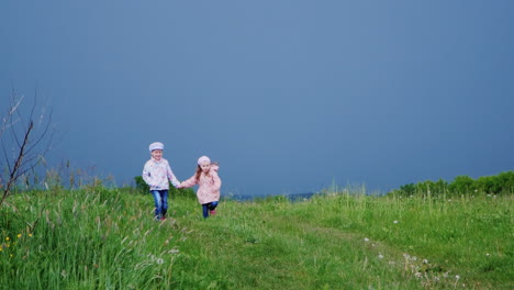Two-cheerful-girls-run-hrough-the-meadow-holding-hands