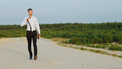 A-businessman-with-a-bottle-of-alcohol-walks-forward-on-the-sand-1
