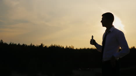 Silhouette-of-a-businessman-drinking-alcohol-at-sunset
