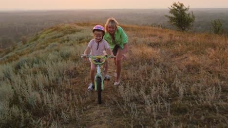 Mother-teaches-her-daughter-to-ride-a-bicycle