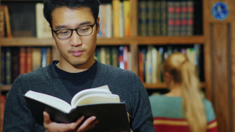 Good-Looking-Asian-Man-In-Glasses-Reading-A-Book-In-The-Library-1