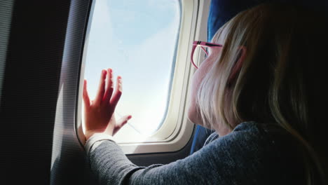 A-6-Year-Old-Girl-With-Spectacles-Sits-In-A-Plane-Looking-Out-The-Window