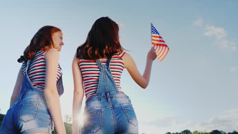 Zwei-Weibliche-Zwillinge-Mit-Einer-Amerikanischen-Flagge-Auf-Blauem-Himmelshintergrund-1