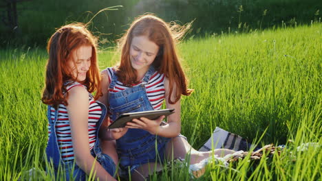 Two-Twin-Sisters-Use-A-Tablet-Outdoors