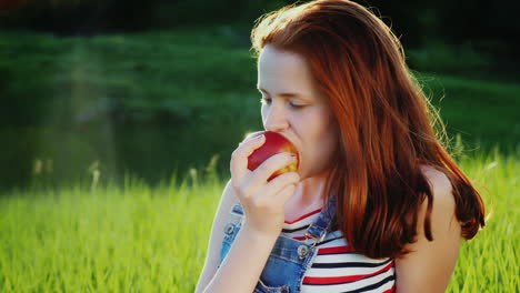 Adolescente-Pelirroja-Comiendo-Una-Jugosa-Manzana-Roja-En-Un-Picnic