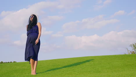 A-Pregnant-Woman-In-A-Light-Dress-Carefree-Walks-Through-A-Green-Meadow