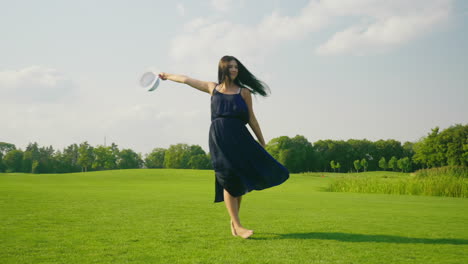 A-Stylish-Pregnant-Woman-In-A-Light-Dress-Carefree-Walks-Along-A-Green-Meadow-Past-The-Camera